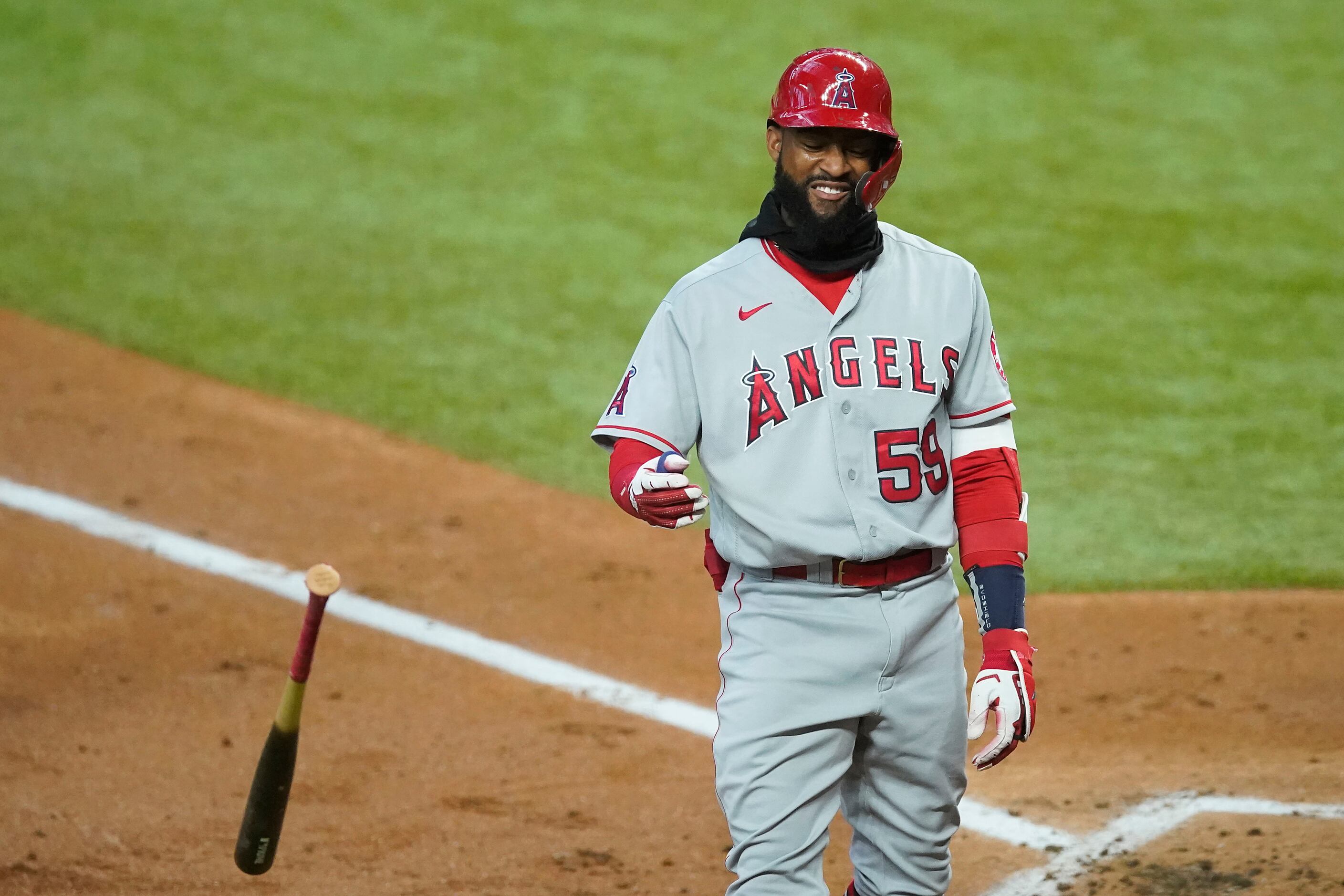 Los Angeles Angels center fielder Jo Adell tosses his bat after what initially looked like...