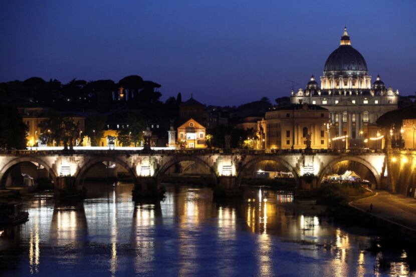 St. Peter's Basilica in Vatican City is seen illuminated at night beyond St. Angelo's...