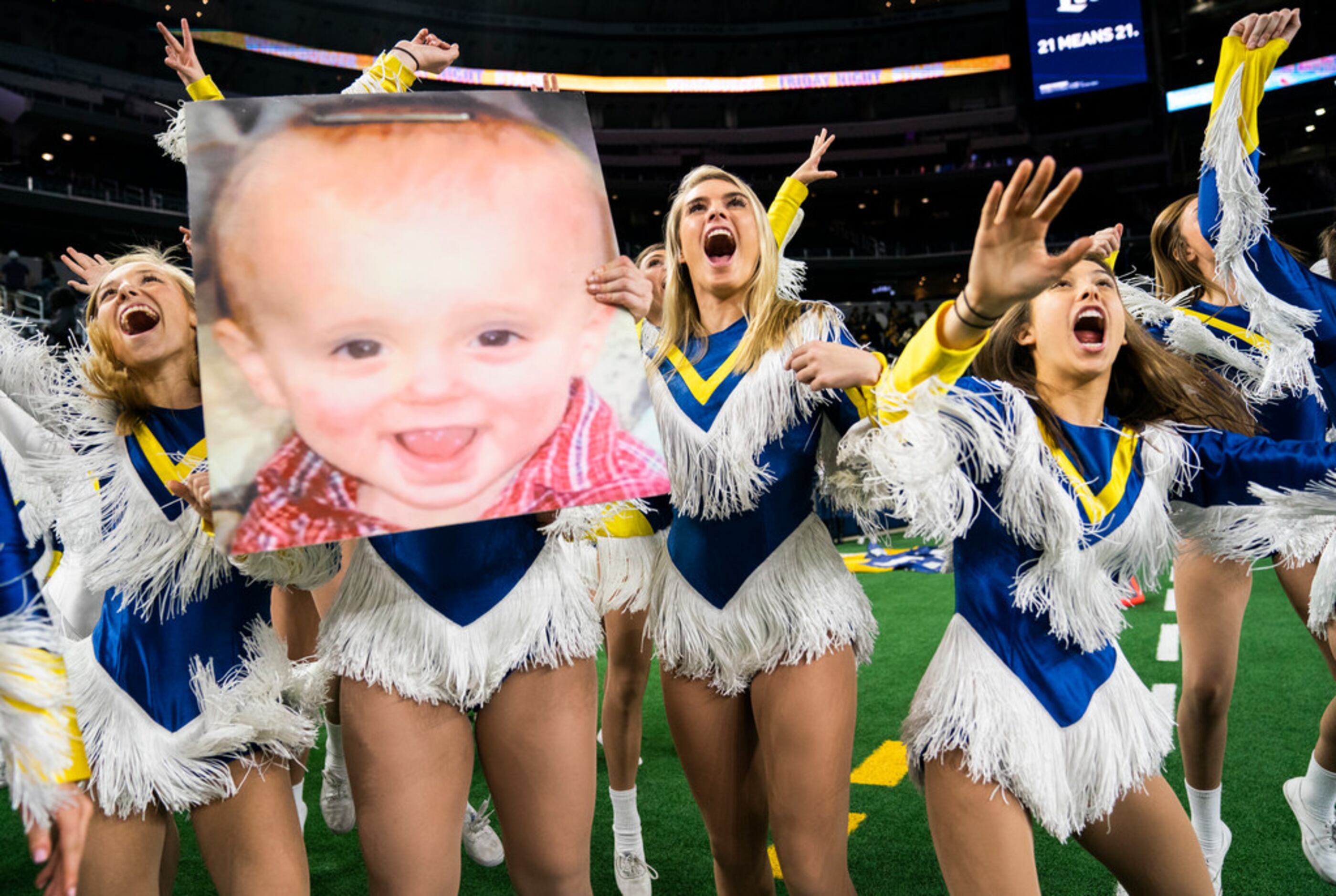 Highland Park dance team members hold a photo of a baby as they celebrate a 63-28 win over...