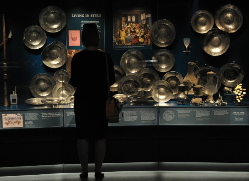 A museum employee stands next to pewter plates found on the wreck of the Tudor warship Mary...