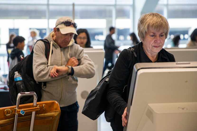 Kelcie Hibbs (right), from Fort Worth, Texas, utilizes an American Airlines electronic kiosk...