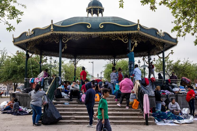 Expelled migrants mill around a gazebo in a public square in the Mexican border city of...