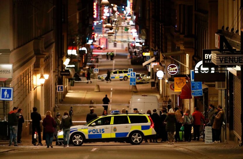 People stand behind the police cordon as they work at the scene after a truck slammed into a...