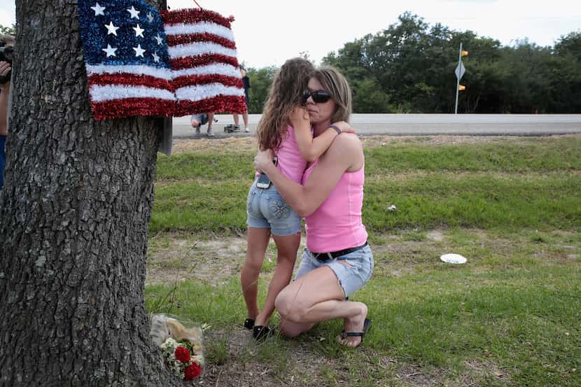 Carissa Potts hugs her 7-year-old daughter, Kaylee, after leaving flowers at a small...
