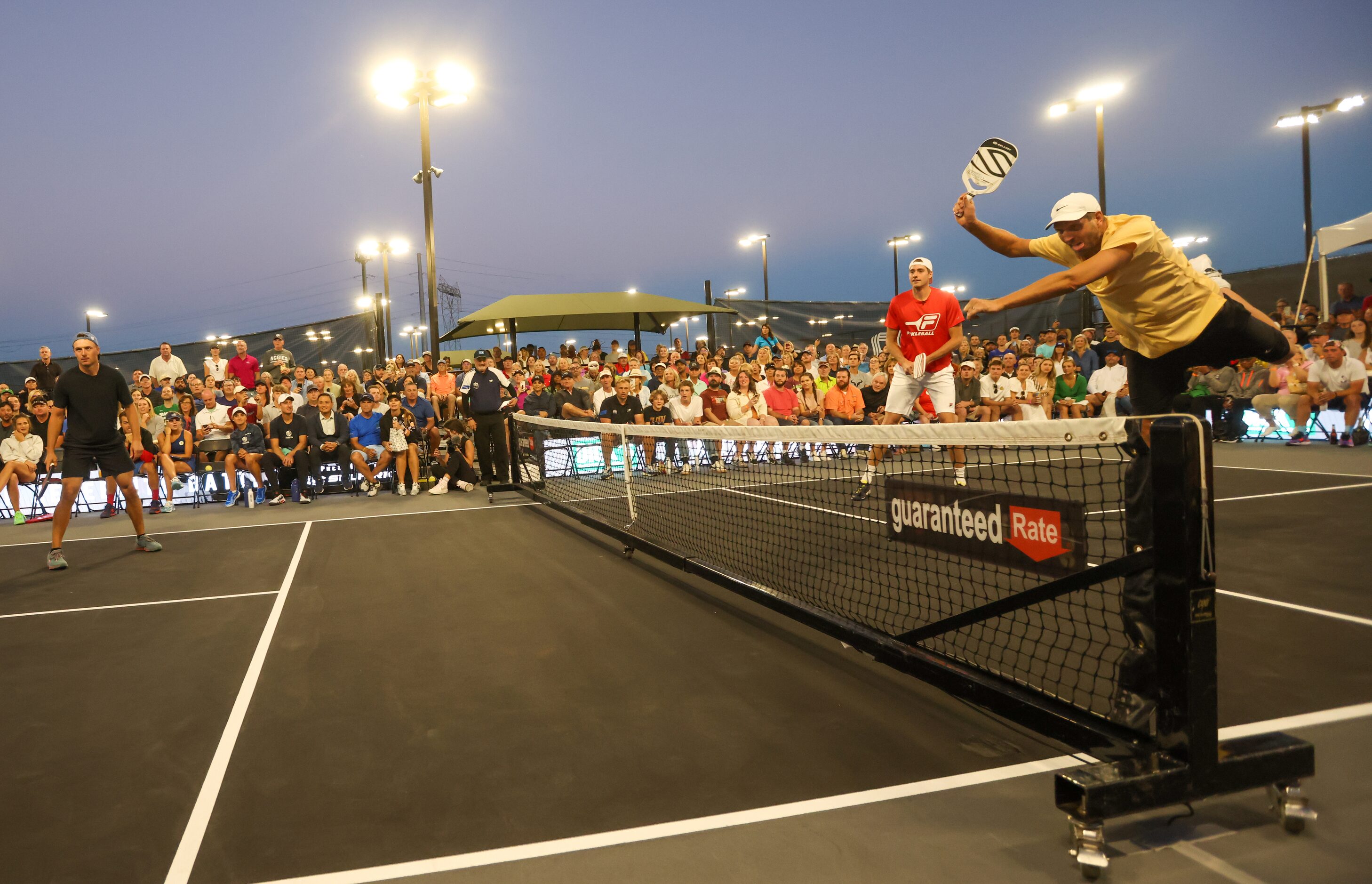 Dirk Nowitzki (right) begins to fall after hitting the ball over the net in a doubles match...