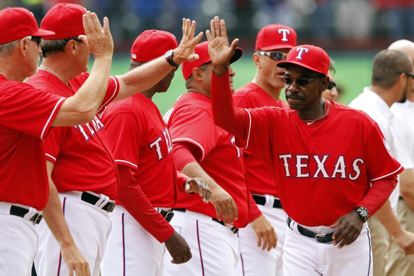 Texas Rangers manager Ron Washington (38) slaps hands with teammates during team...