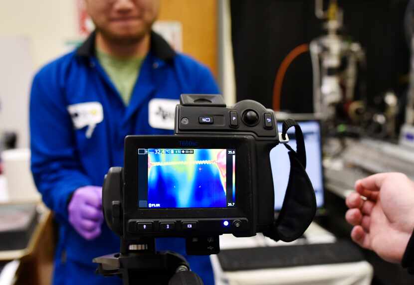 Research scientist Jiuke Mu holds a piece of rubber and twists the fibers to cool them down....