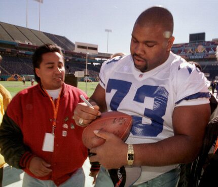 Larry Allen pone su autógrafo en un balón unos días antes de que se jugara el Super Bowl XXX...