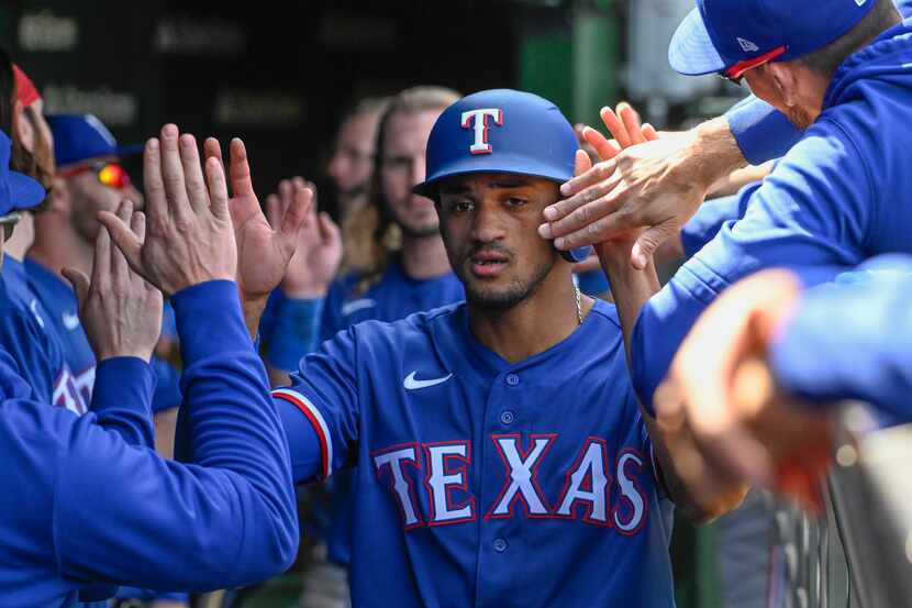 Texas Rangers' Bubba Thompson, center, celebrates in the dugout after scoring during the...