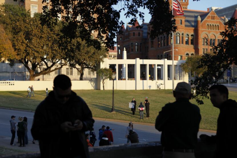 As the sun set, people gathered at the grassy knoll at Dealey Plaza for the anniversary of...