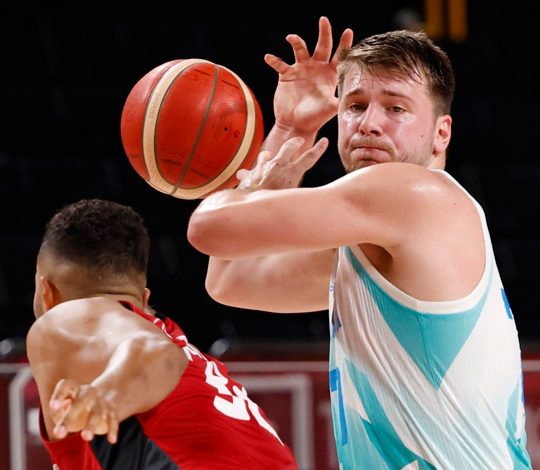 Slovenia’s Luka Doncic (77) gets the ball knocked away by Germany’s Johannes Thiemann (32)...