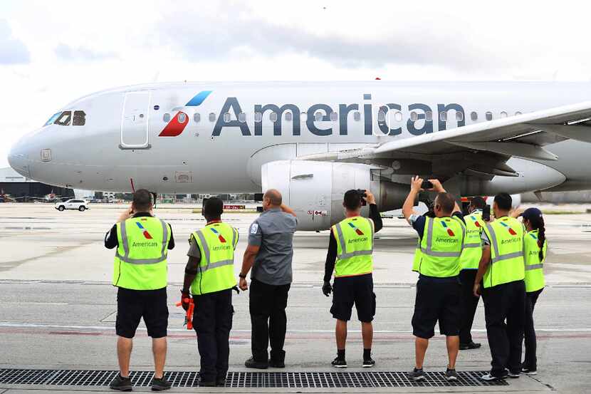 Employees watch as American Airlines Flight 903 prepares for take off, becoming the first...