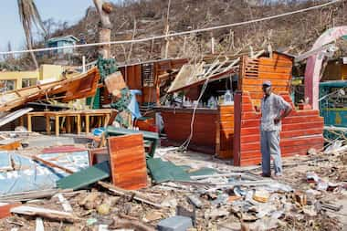 A man stands next to a business destroyed by Hurricane Beryl in Clifton, Union Island, St....