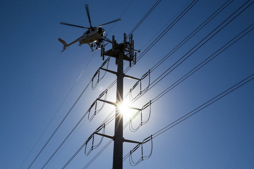 Helicopter linemen for an Oncor contractor work on transmission lines near Royal Lane at...