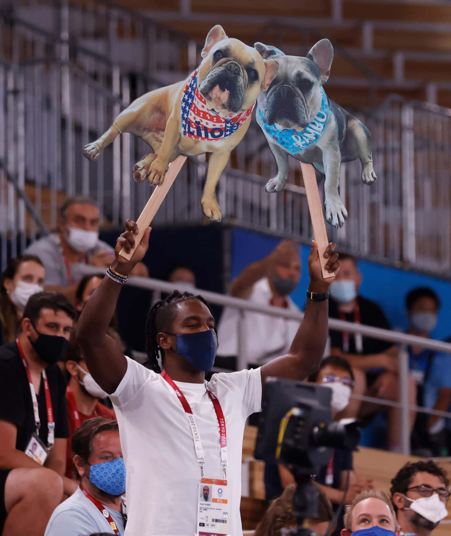 Scott Evans, host of Access Hollywood holds up cardboard cutouts of USA’s Simone Biles dogs...