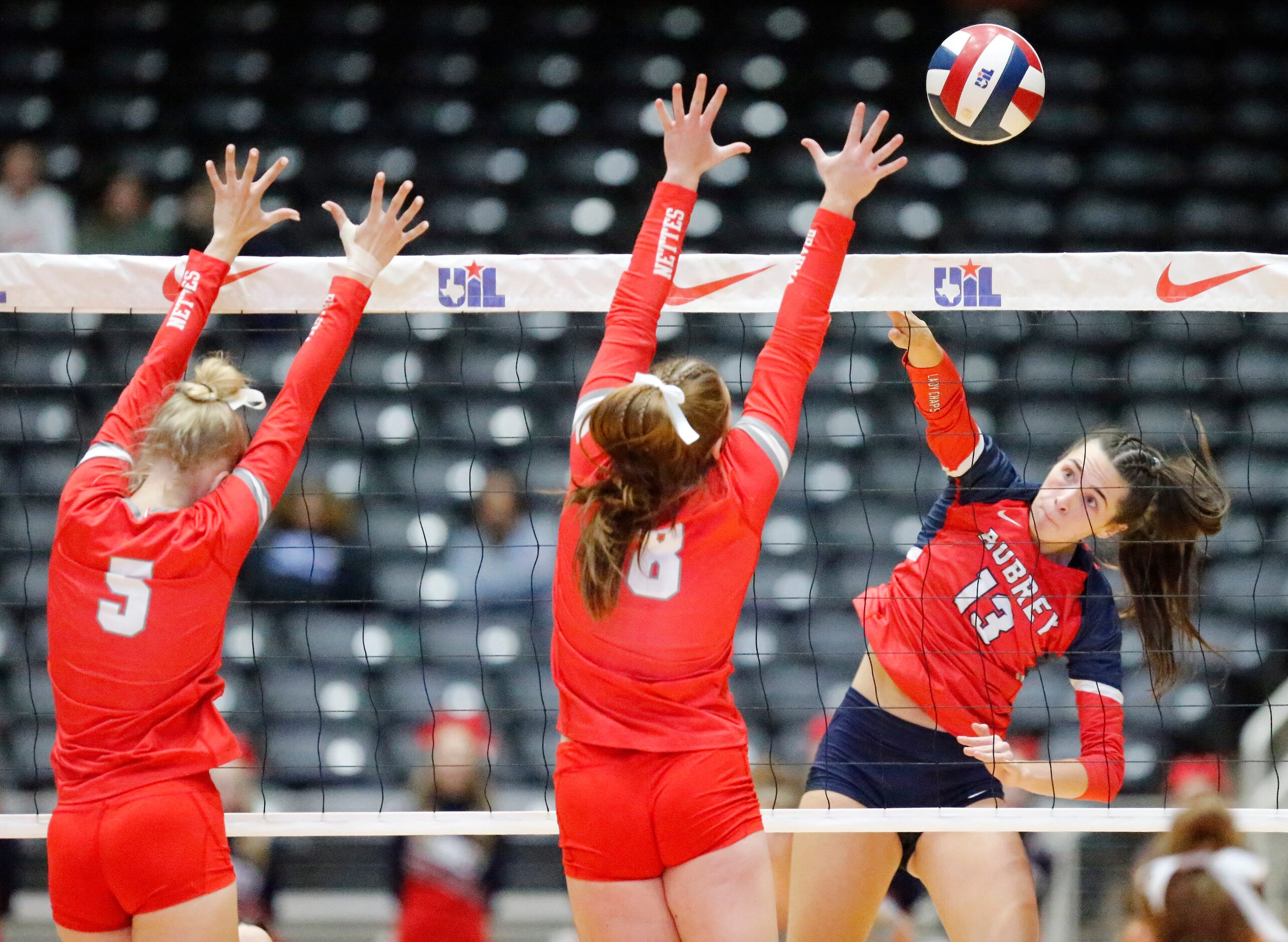 Aubrey High School outside hitter Sydney Garrison (13) gets a hit past Bellville High...