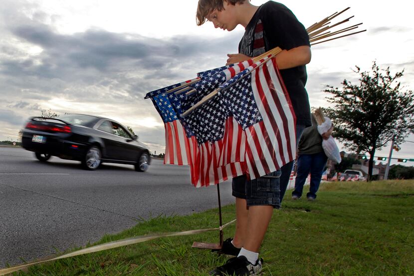 Justin Lindamood helps place flags along with his brother and others, along roadway on North...
