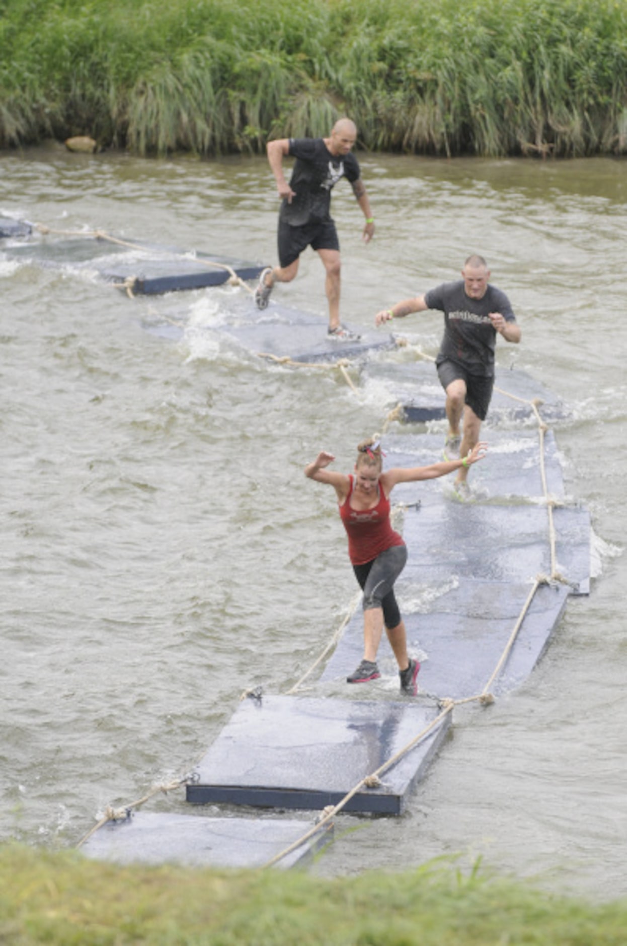 Participants in the Original Mud Run cross the Trinity River on floating pads during the...