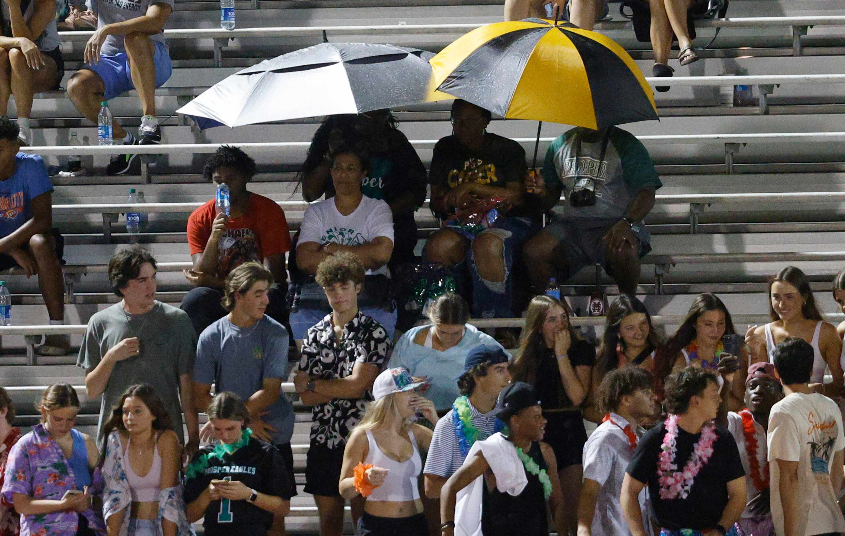 People hold umbrellas during the second half of a high school football game between Rockwall...