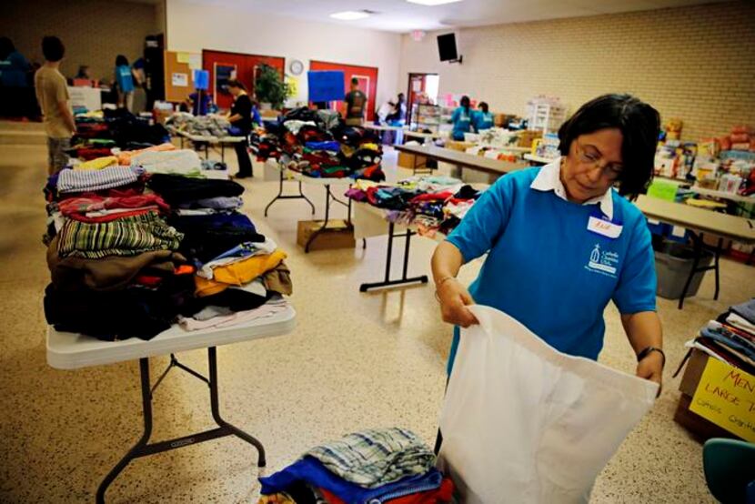
Ana Hallaman helps fold clothing at Sacred Heart Catholic Church Wednesday, July 2, 2014 in...