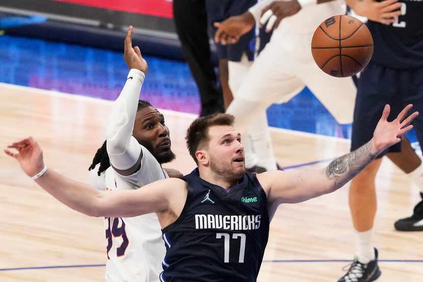 Dallas Mavericks guard Luka Doncic (77) grabs a rebound in front of Phoenix Suns forward Jae...