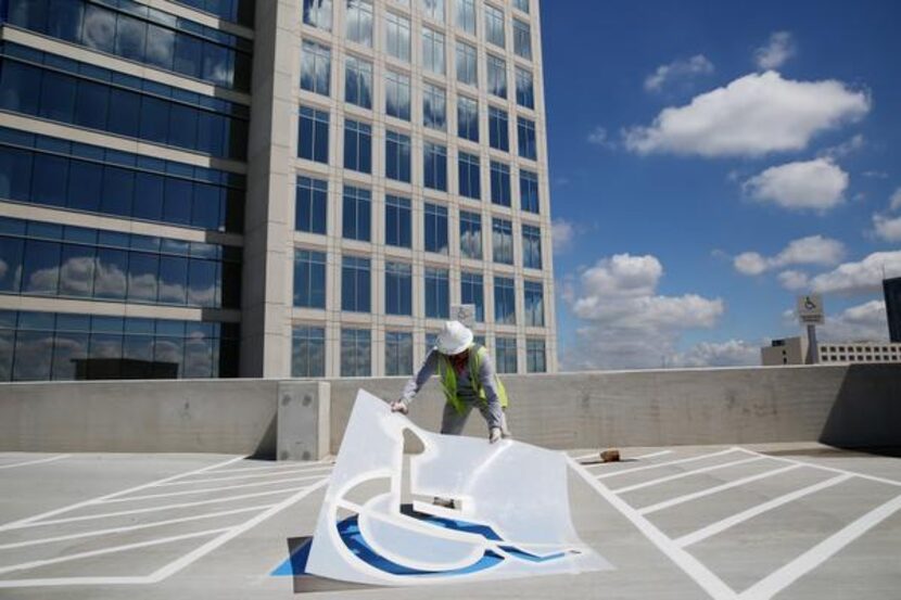 
Enrique Acosta of Dallas paints a parking space atop the parking garage at the Granite Park...