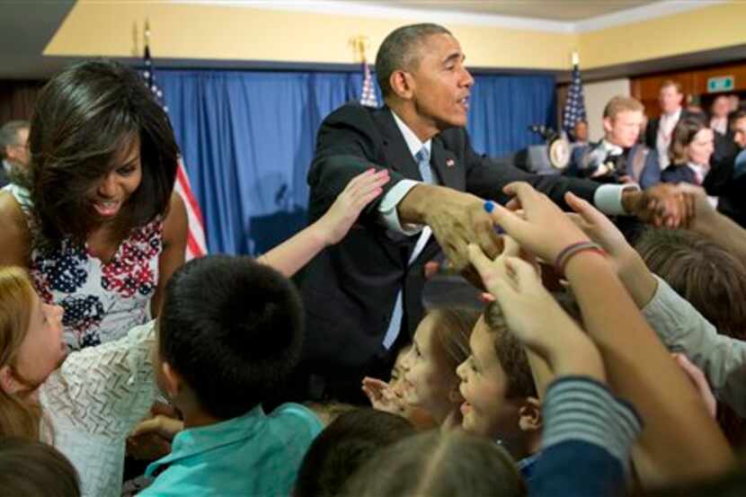 El presidente Barack Obama y su esposa Michelle saludan con niños, hijos del personal de la...