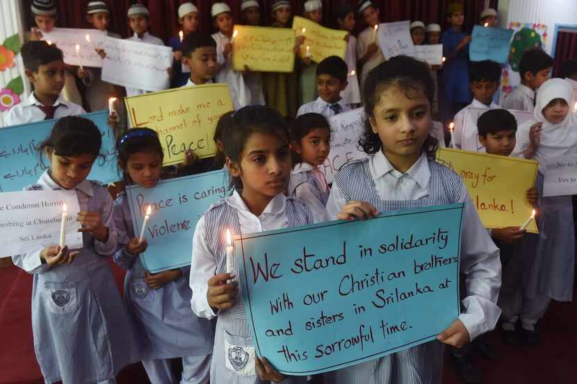 Pakistani Christian and Muslim students carry placards and candles as they pay tribute to...