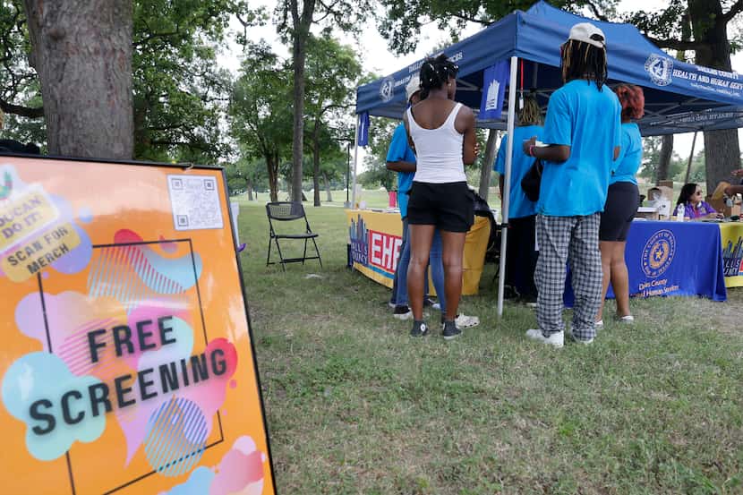 People gather around a registration tent during an HIV testing event at Glendale Park,...