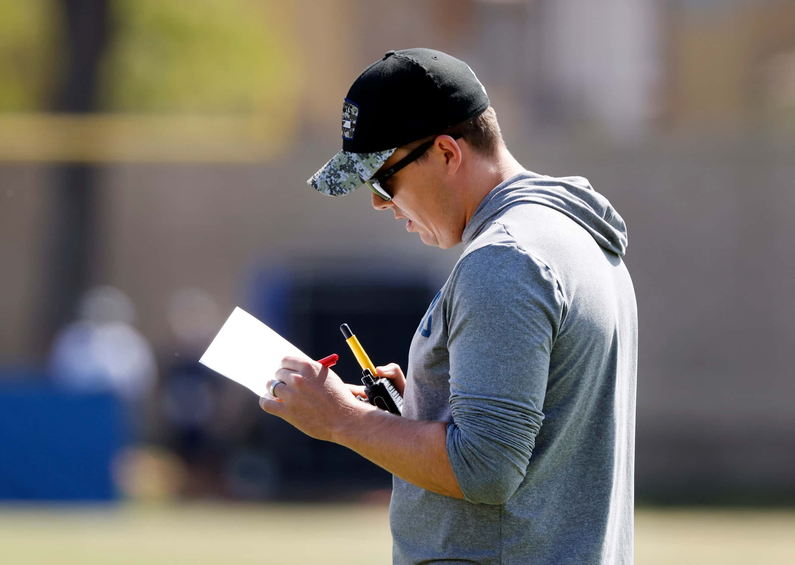 Dallas Cowboys offensive coordinator Kellen Moore studies his play sheet during a mock game...
