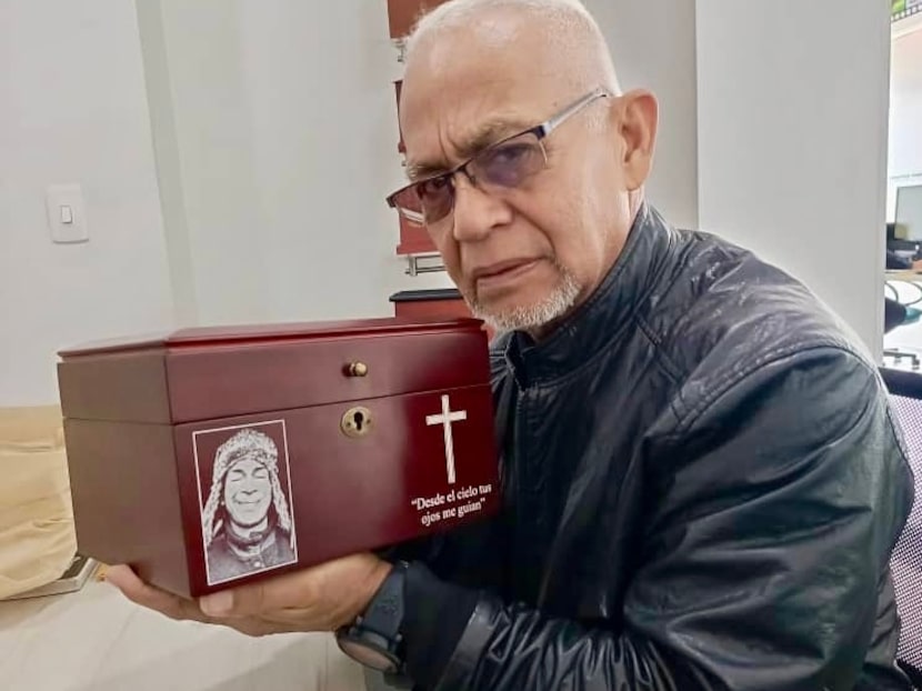 Santos Cumana holds the urn with the ashes of his son, Elio David Cumana Rivas, on August 4,...