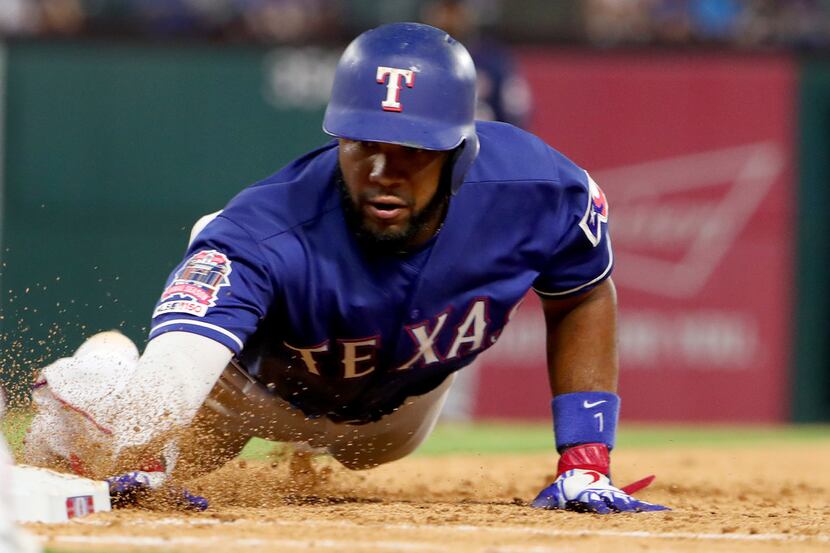 ARLINGTON, TEXAS - AUGUST 16: Elvis Andrus #1 of the Texas Rangers dives back to first base...