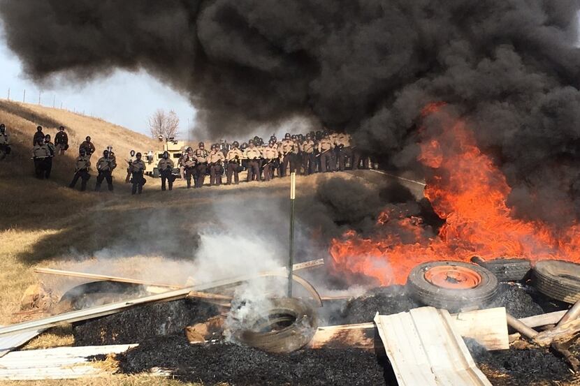 Tires burn as armed soldiers and law enforcement officers stand in formation on Thursday to...