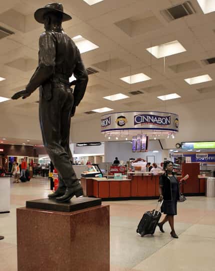 A traveler heads to security at Dallas Love Field, and past the famous Texas Ranger statue...
