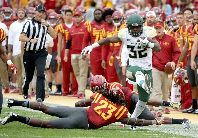 Baylor running back Shock Linwood high steps through Iowa State defensive back Thadd Daniels...