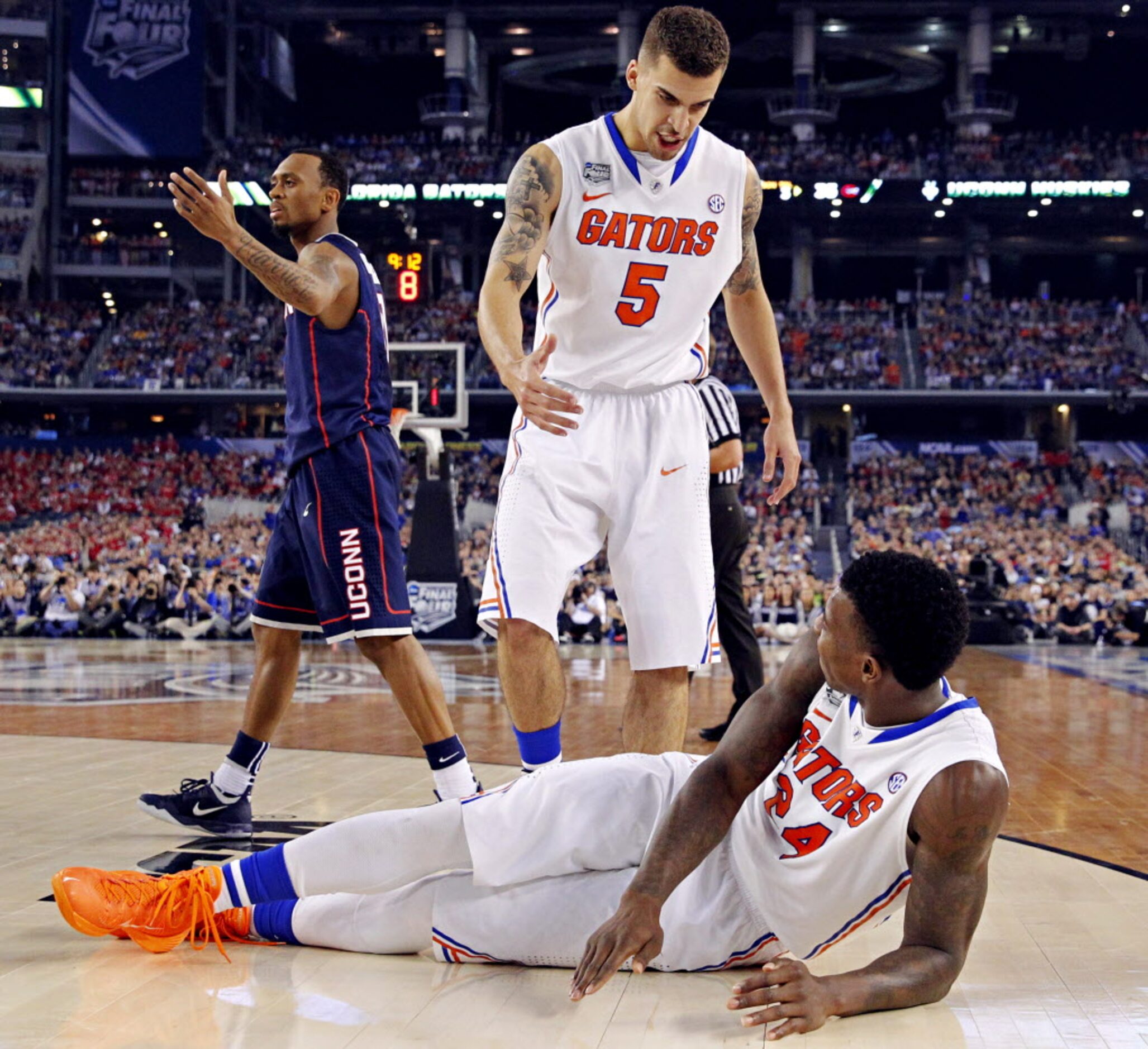 Florida Gators guard Scottie Wilbekin (5) walks over to help forward Casey Prather (24) up...