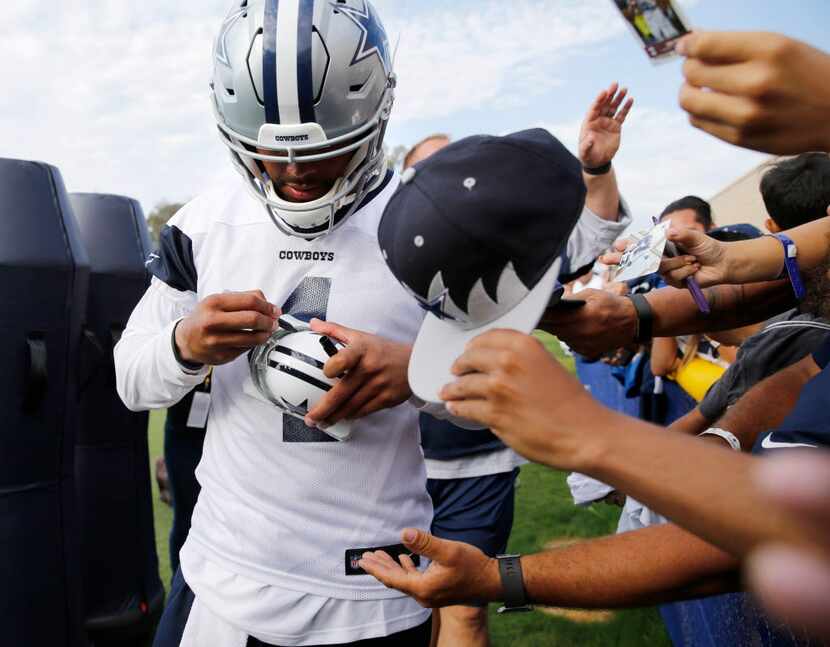 Dallas Cowboys quarterback Dak Prescott (4) signs a helmet after the afternoon practice at...