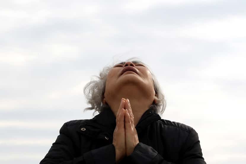 A weeping relative of a passenger aboard the sunken Sewol ferry prays as she awaits news on...
