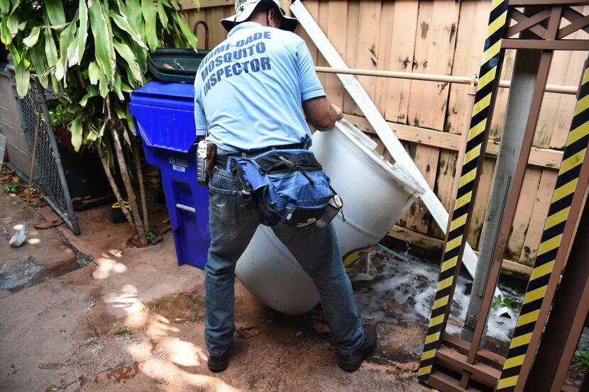 A Miami-Dade mosquito control worker  dumps a barrel of standing water that can incubate the...