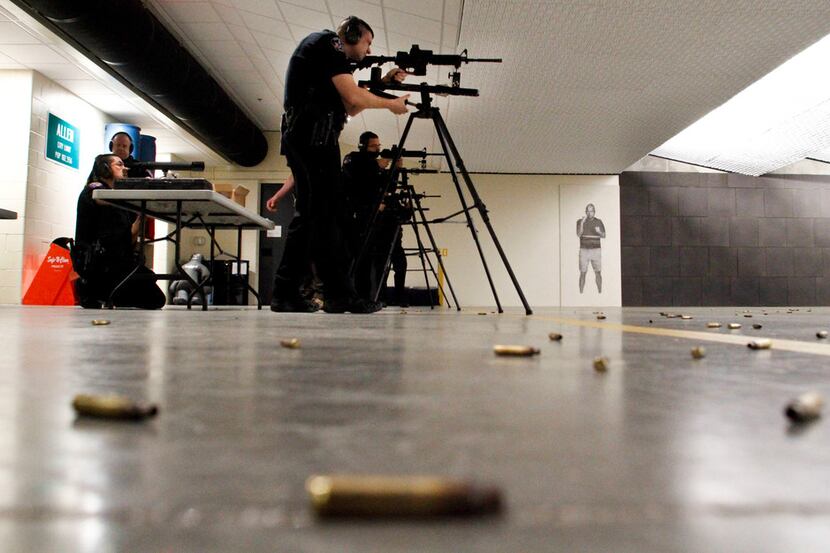 John Booth, a school resource officer with the Allen Police Department, sights in his rifle...
