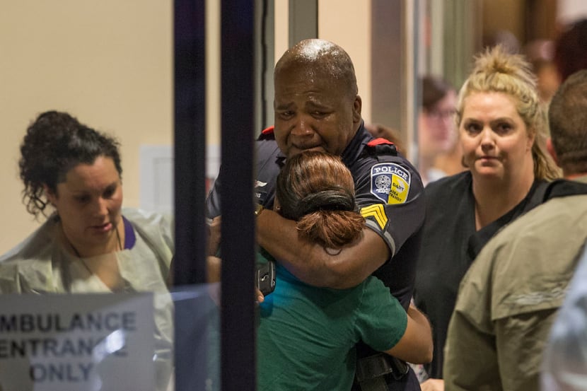 DART police Sgt. Homer Hutchins (center) hugged DART Officer Shamika Sorrells in the hallway...