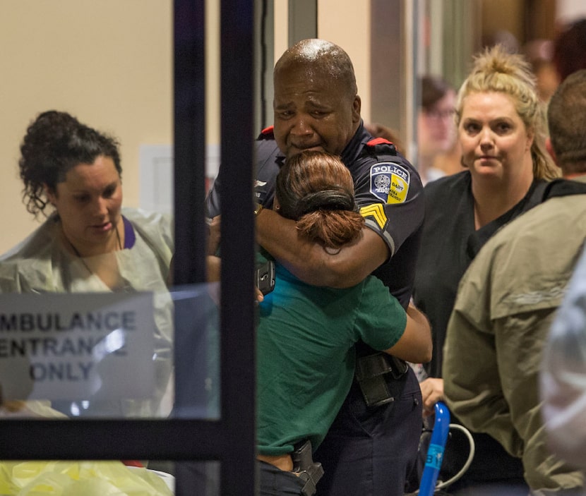 DART police Sgt. Homer Hutchins (center) hugged DART Officer Shamika Sorrells in the hallway...