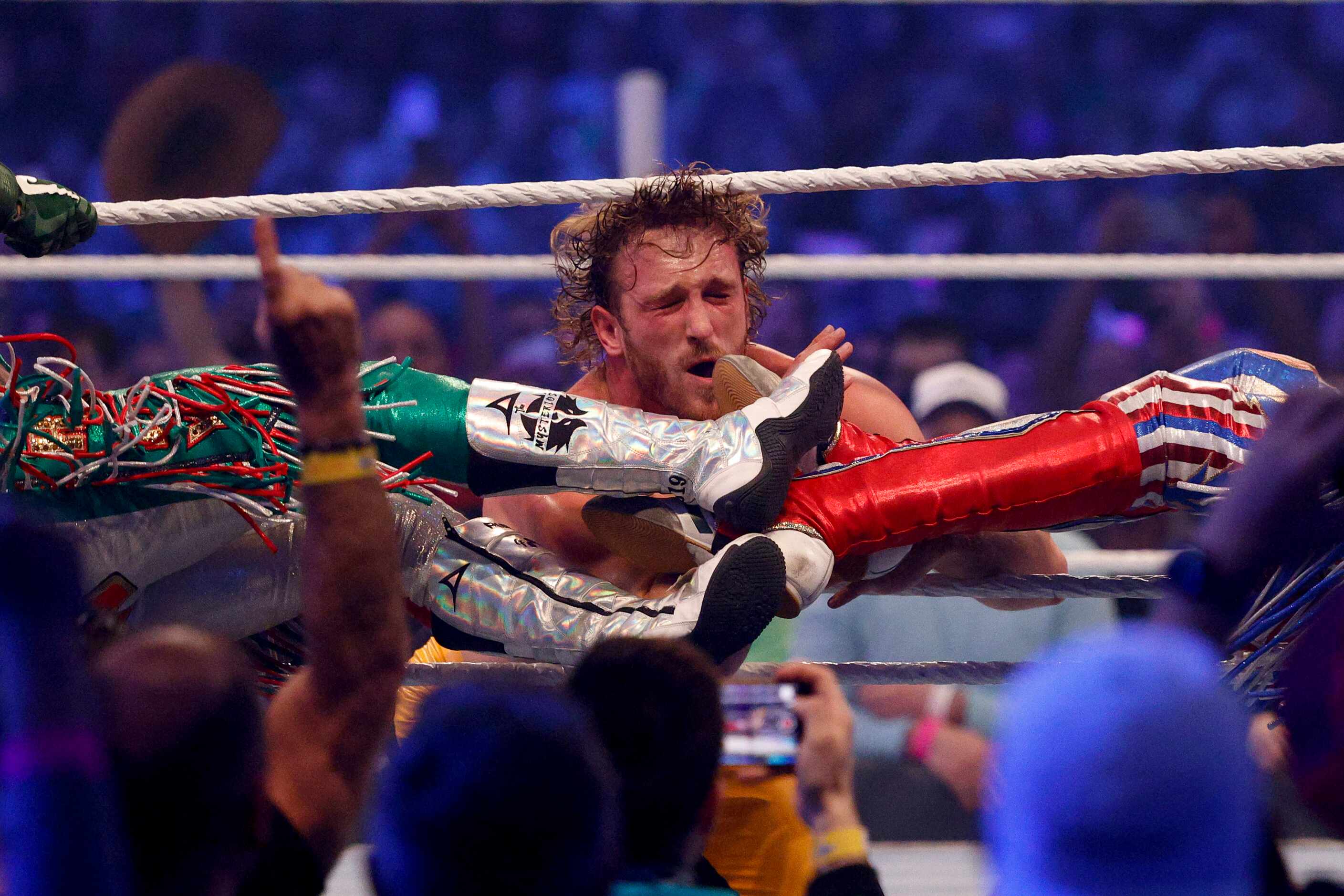 Logan Paul takes a set of kicks to the face from Rey and Dominik Mysterio during...