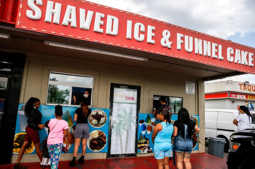 People line up to cool off with shaved ice in the Pleasant Grove neighborhood on Friday in...