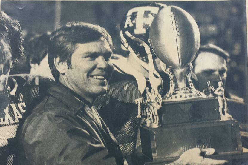 Texas A&M coach Tom Wilson holds up the Independence Bowl trophy after the Aggies defeated...