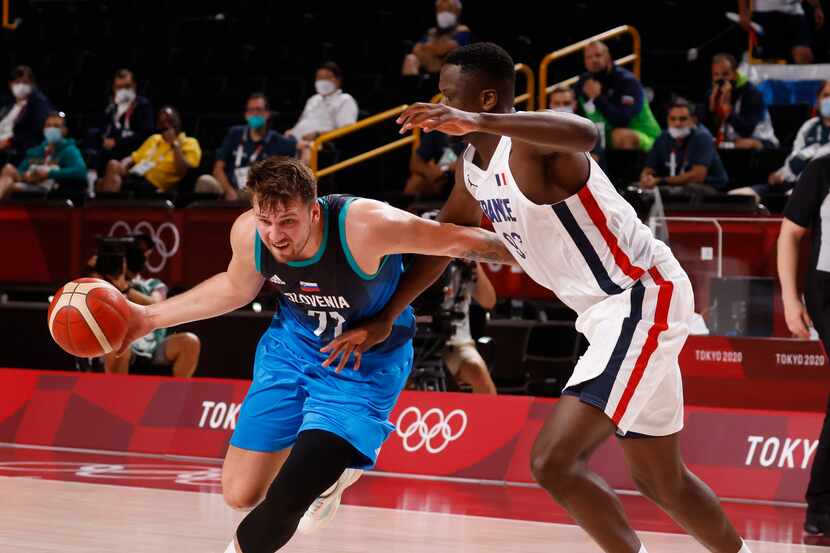Slovenia’s Luka Doncic (77) drives to the basket as he is defended by France’s Moustapha...