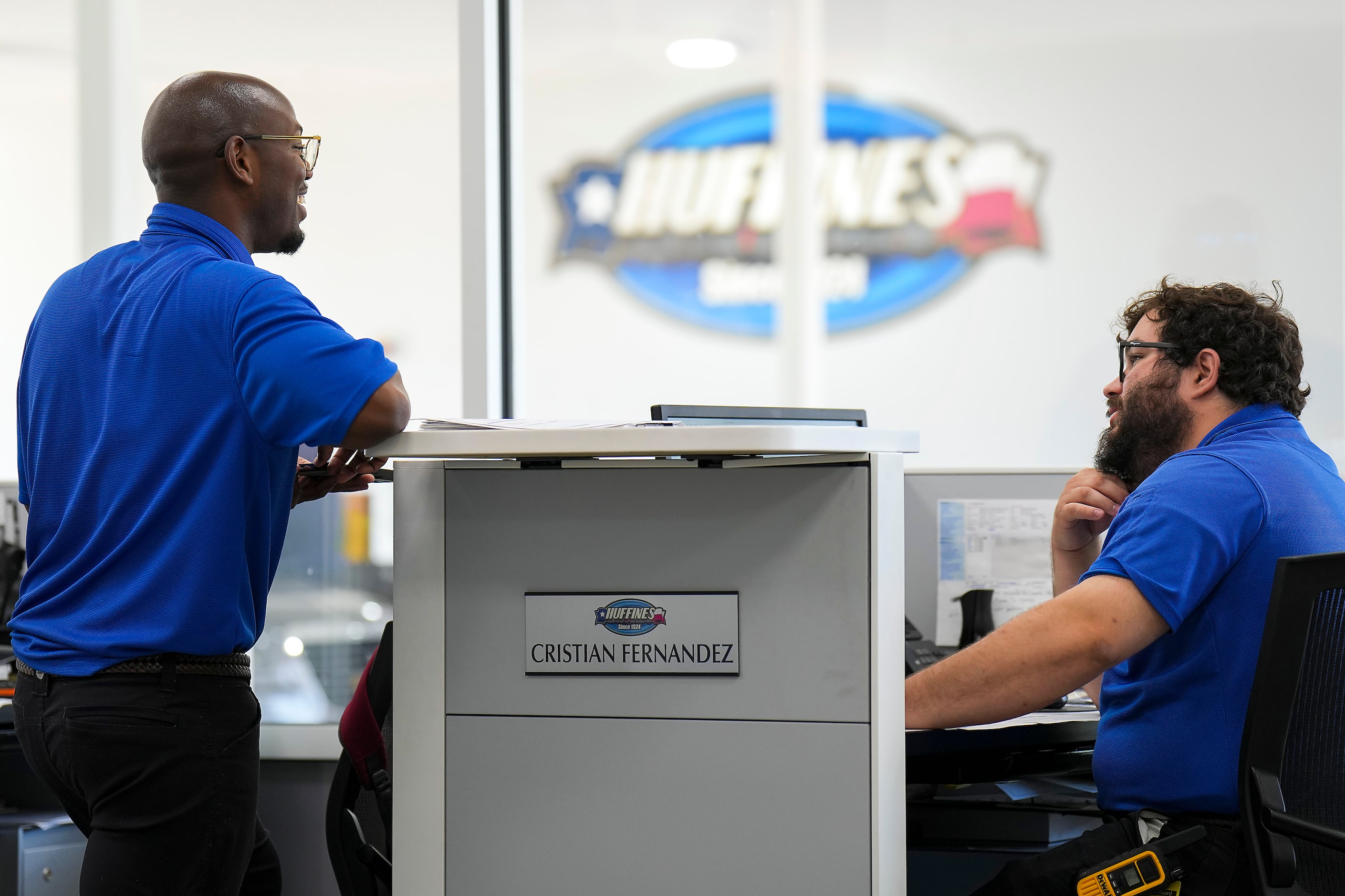 Service advisers Kelsey Shepard (left) and Cristian Fernandez chat at their desks at...