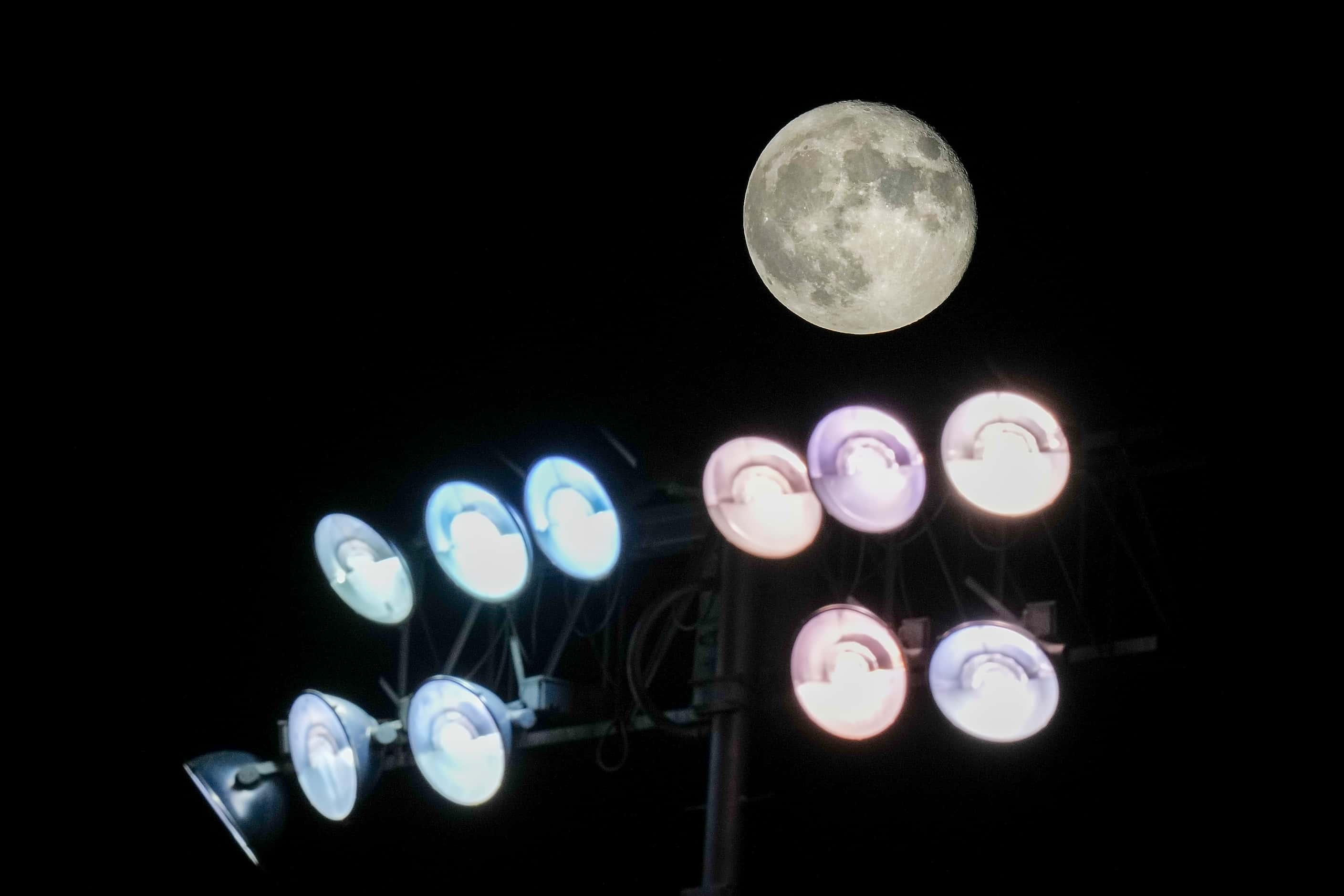 The moon rises over the lights of the stadium during the second half of a high school...