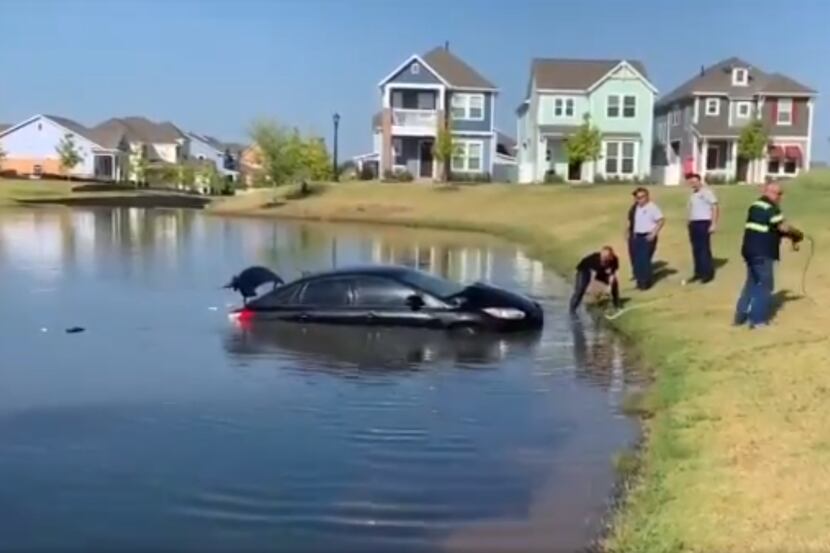 A black sedan is towed from a lake in North Richland Hills by officials Wednesday morning.