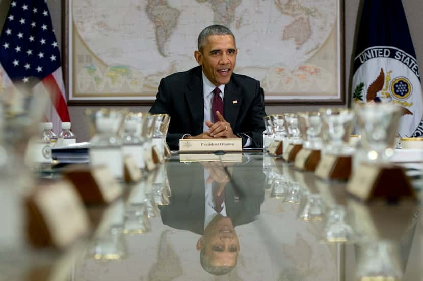 President Barack Obama is reflected in the conference table before a meeting of his National...